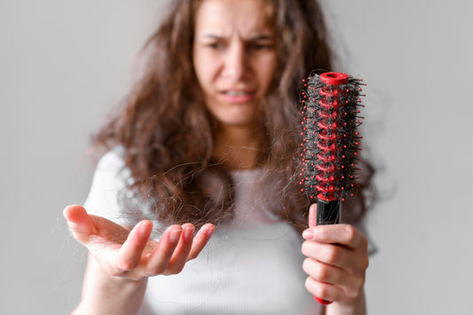 Woman holding a hair brush looking at dry hair.