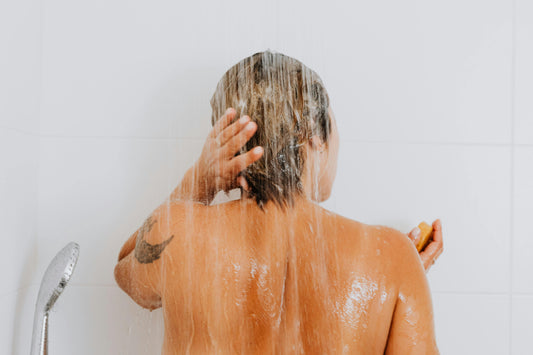 Woman with short hair washing her hair in a shower.