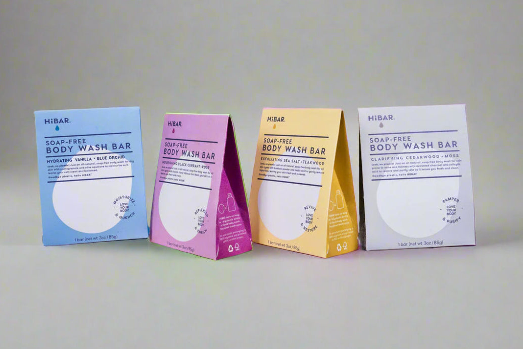 Four body wash bar boxes on a grey background.