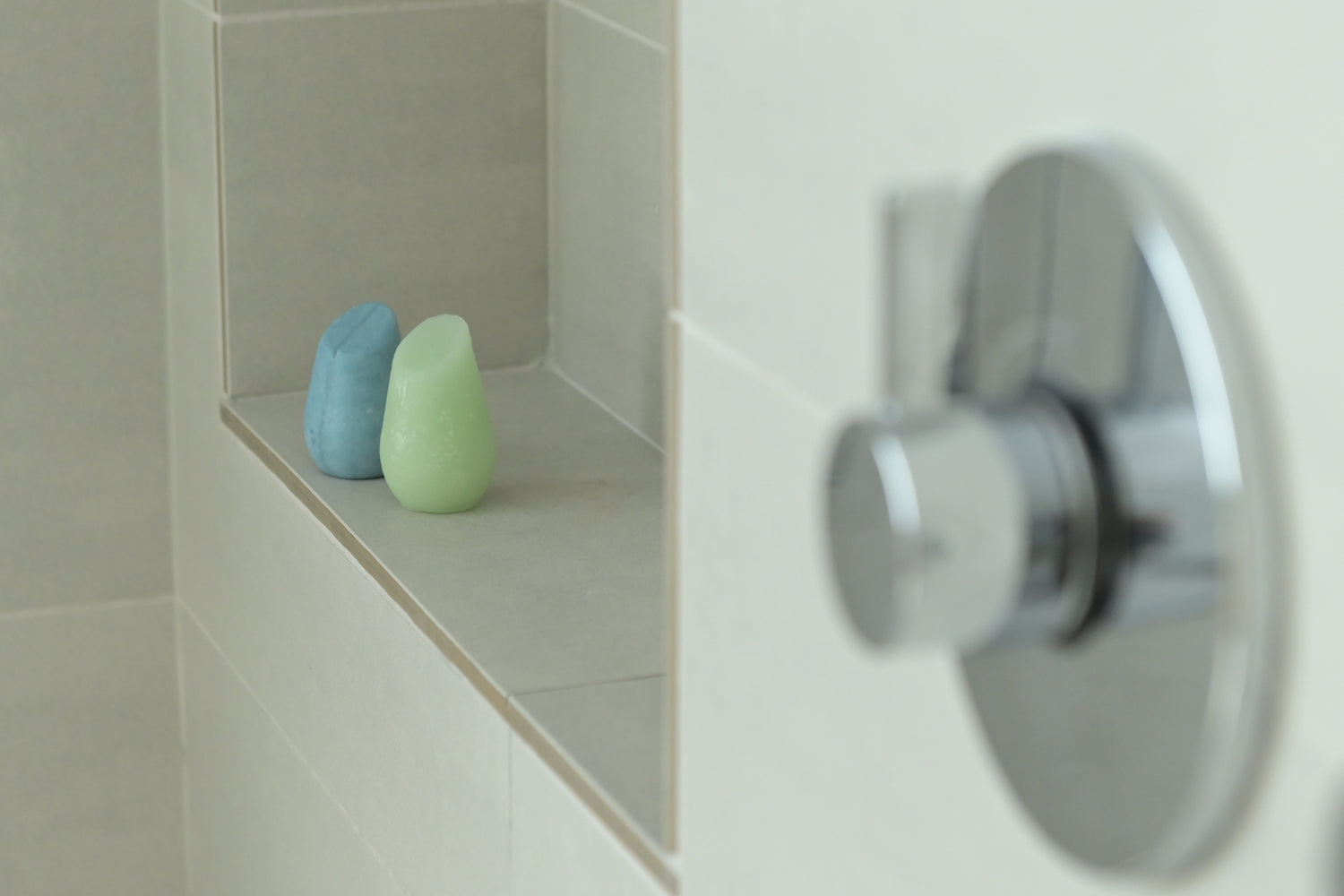 Two shampoo bars on a shower ledge.