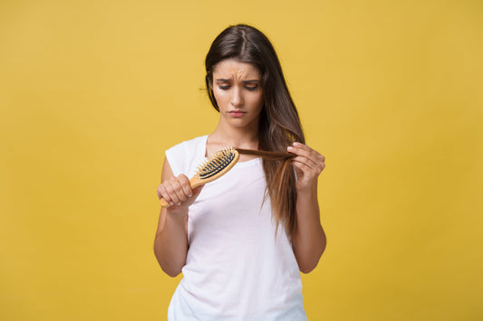 Woman looking at her hair on a yellow background.