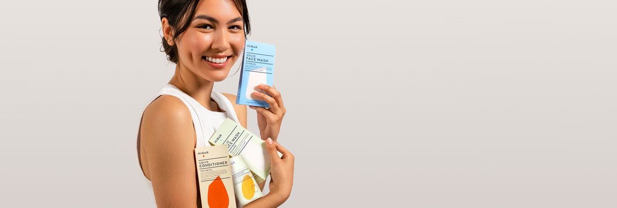 Model with dark hair holding four hibar products. 
