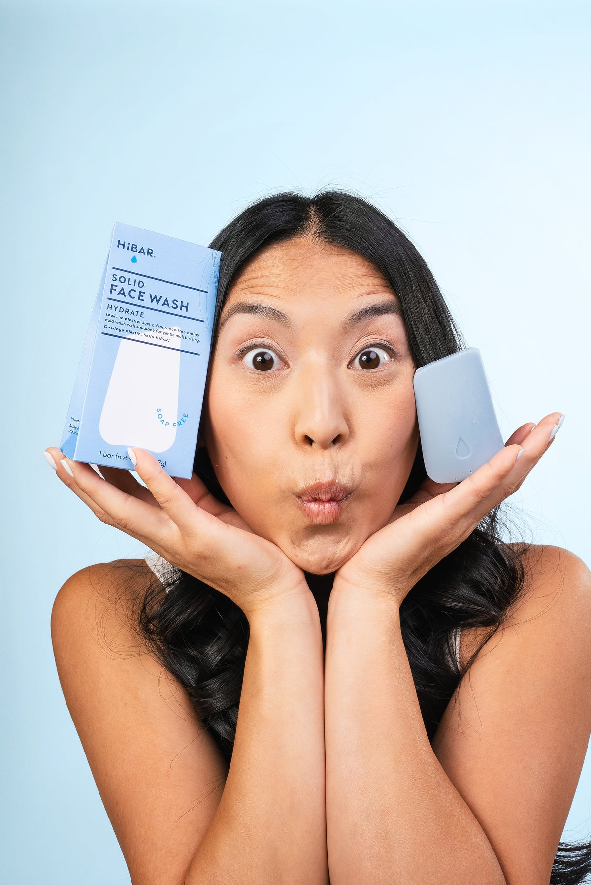 Model holding boxed blue plastic-free face wash bar from Hibar.