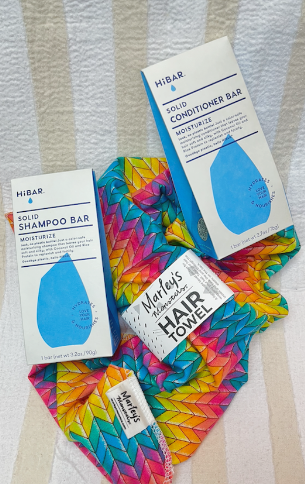 HiBAR hair care products including shampoo bar, conditioner bar, and Marleys monsters towel on a striped background