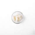 cocoa butter in a glass dish. It is a white looking butter-like solid.